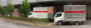 Two Move Move Movers trucks parked along the roadside outside a Singapore commercial building