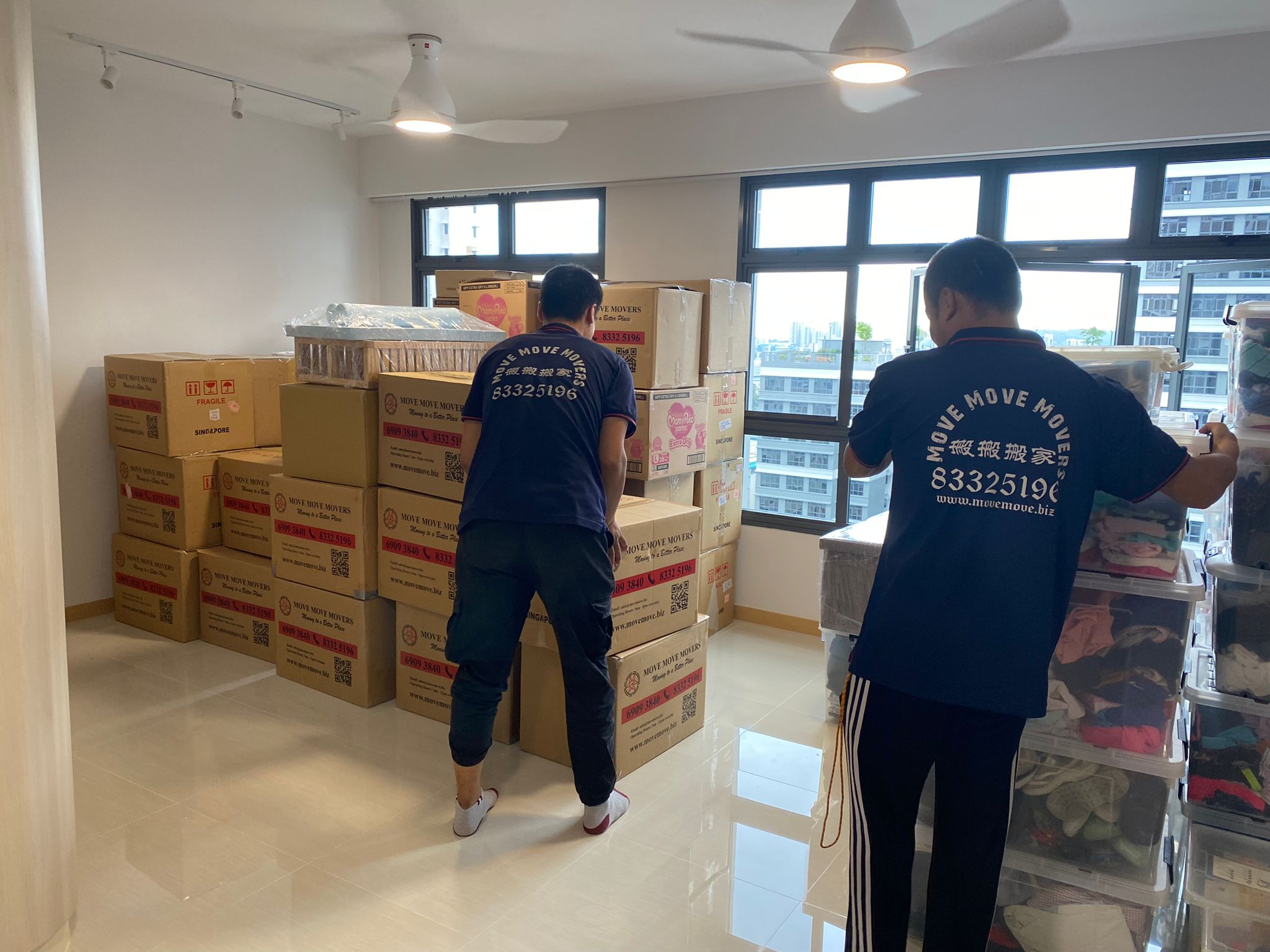 Crew sorting boxed household items inside a residential unit in Singapore