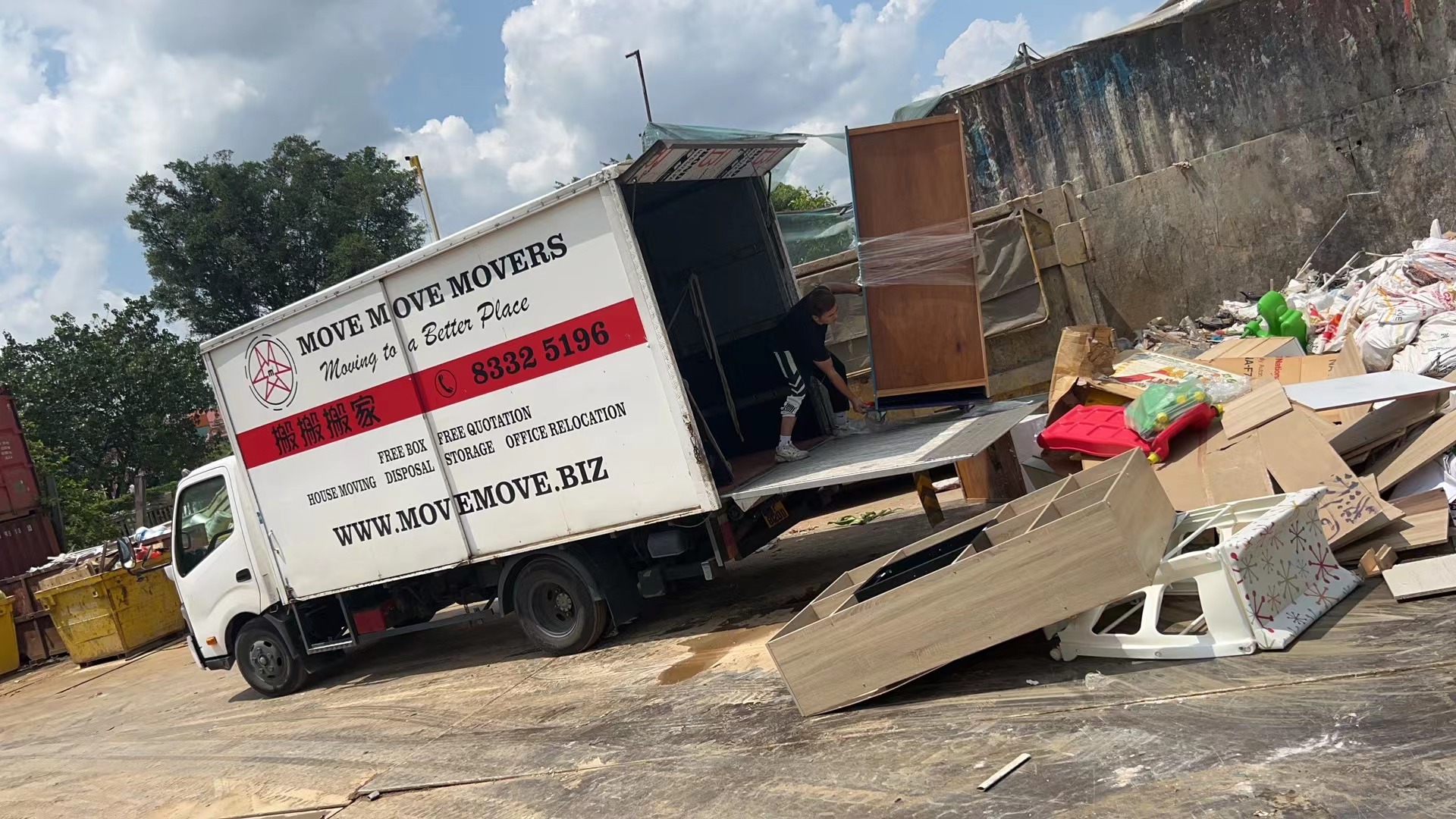 Mixed mattress, furniture and disposal debris staged beside a Singapore disposal truck