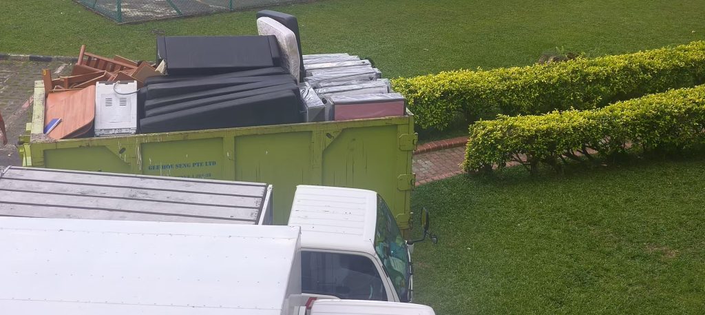 Green skip tank filled with mattresses and bulky furniture at a disposal site