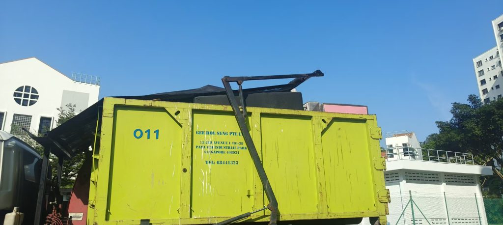 Side view of a green skip tank prepared for bulky-item disposal