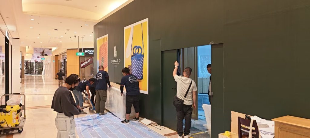Crew aligning wrapped fixtures beside the Goyard storefront during overnight works