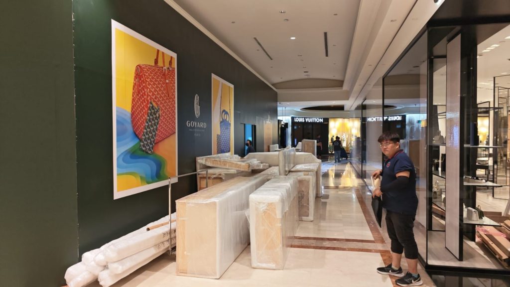 Wrapped fixture modules staged along a corridor wall near storefront entrances