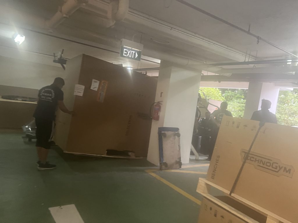 Large Technogym crate being maneuvered around columns in a basement carpark