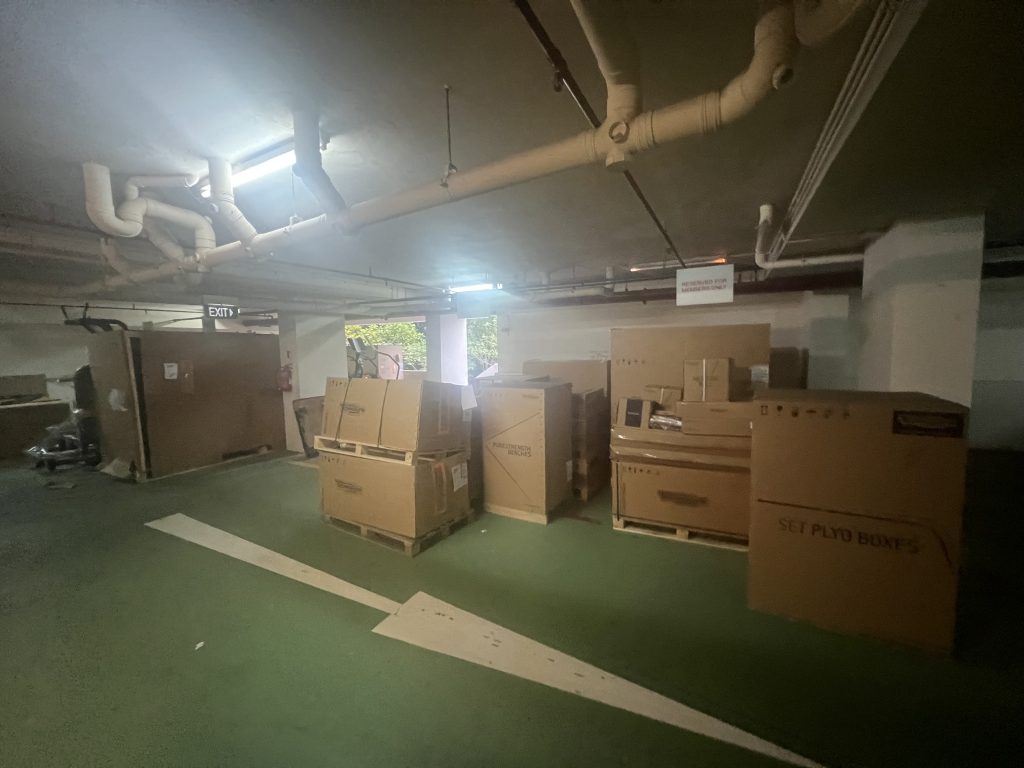 Multiple crated gym-machine components staged in a basement loading area