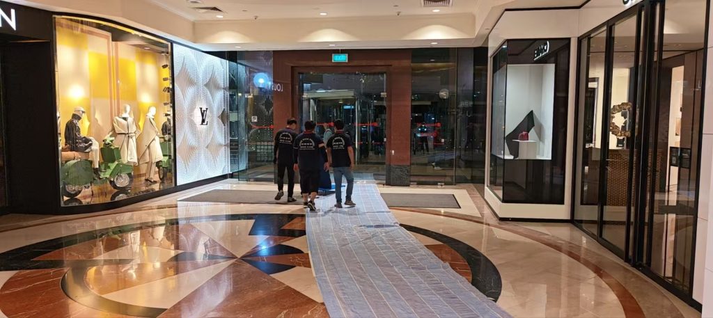 Crew approaching glass exit doors along a protected mall corridor route