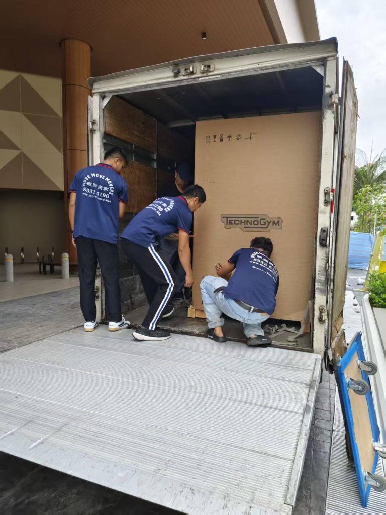Crew positioning and securing an oversized Technogym crate inside a moving truck