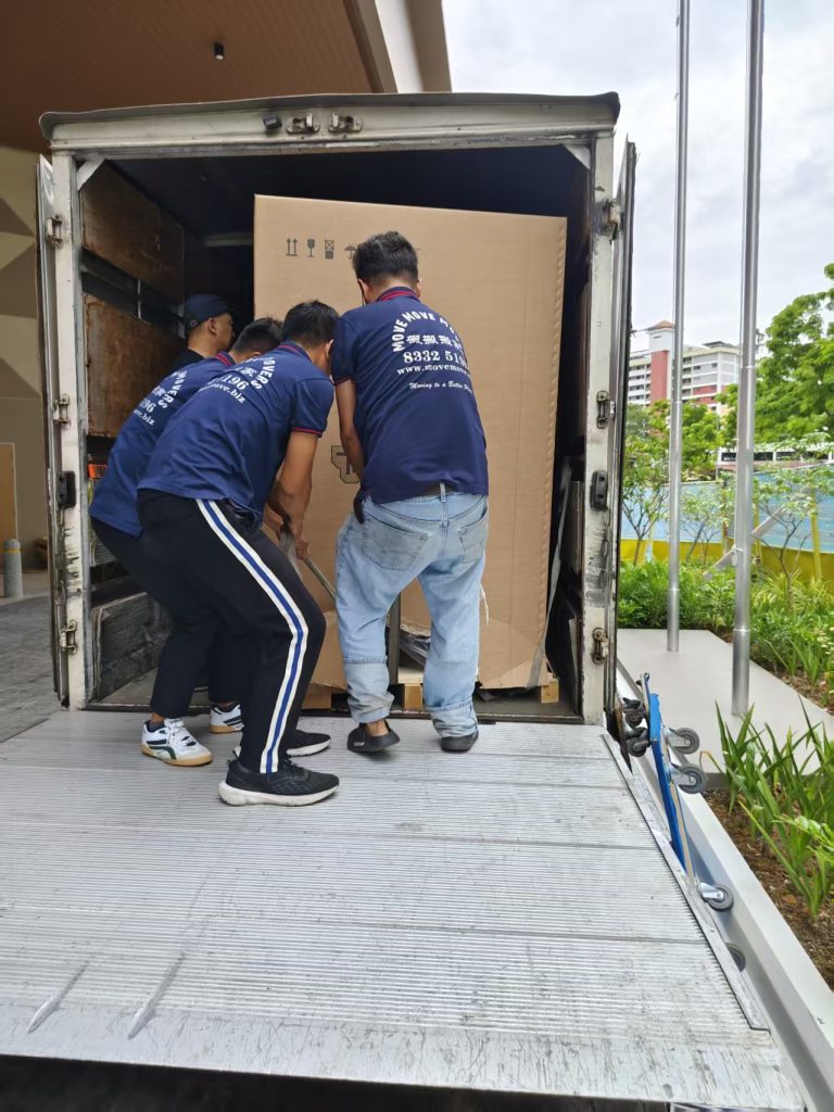 Three movers guiding an oversized boxed Technogym unit onto a lorry tail lift
