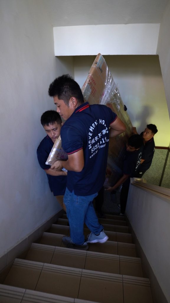 Move Move Movers crew carrying a wrapped furniture piece through a staircase route