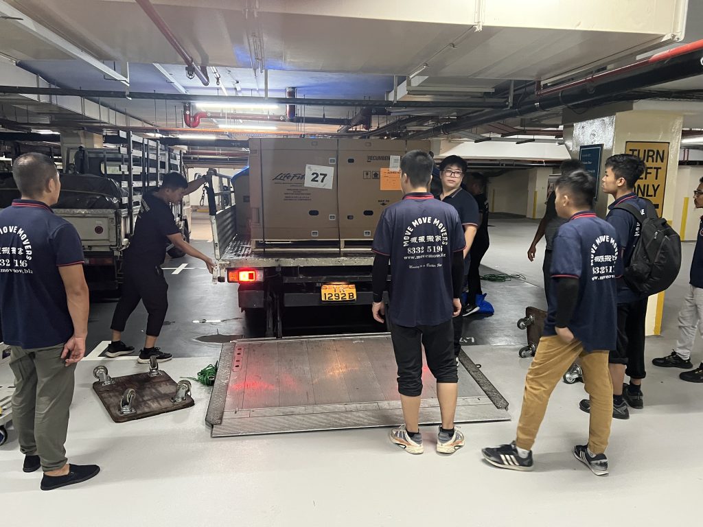 Move Move Movers crew loading boxed fitness equipment via a truck tailgate platform