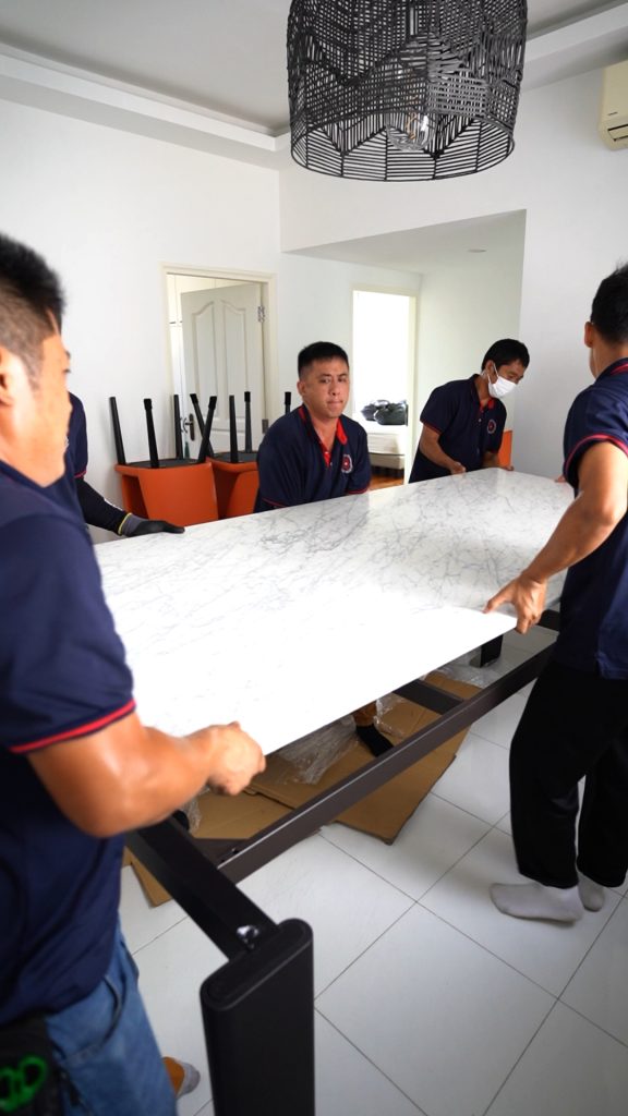 Move Move Movers crew carefully carrying a heavy marble tabletop inside a Singapore home
